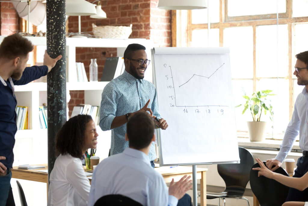 Smiling black leader giving presentation at business seminar, friendly african american mentor speaking at diverse team office training, happy coach talking laughing having fun at group meeting