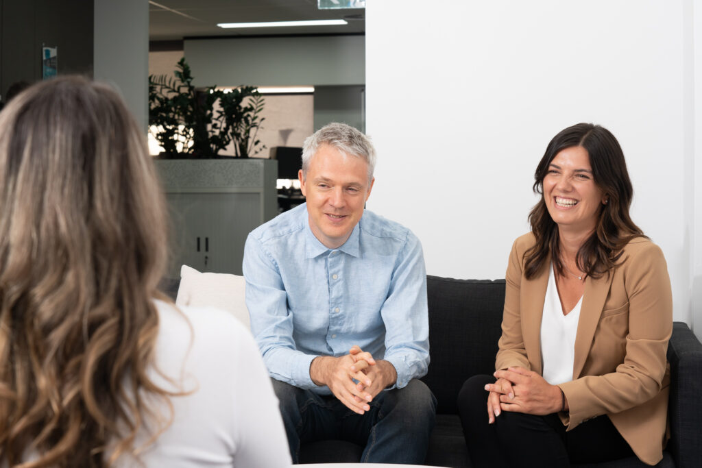 Two individuals engaged in conversation while seated on a comfortable couch, sharing thoughts and ideas.