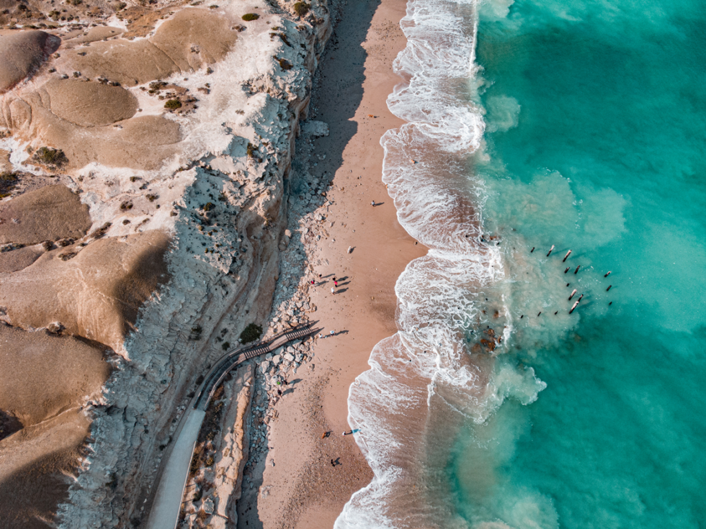 Overhead shot of a beach with golden sand and crystal clear waters of the ocean