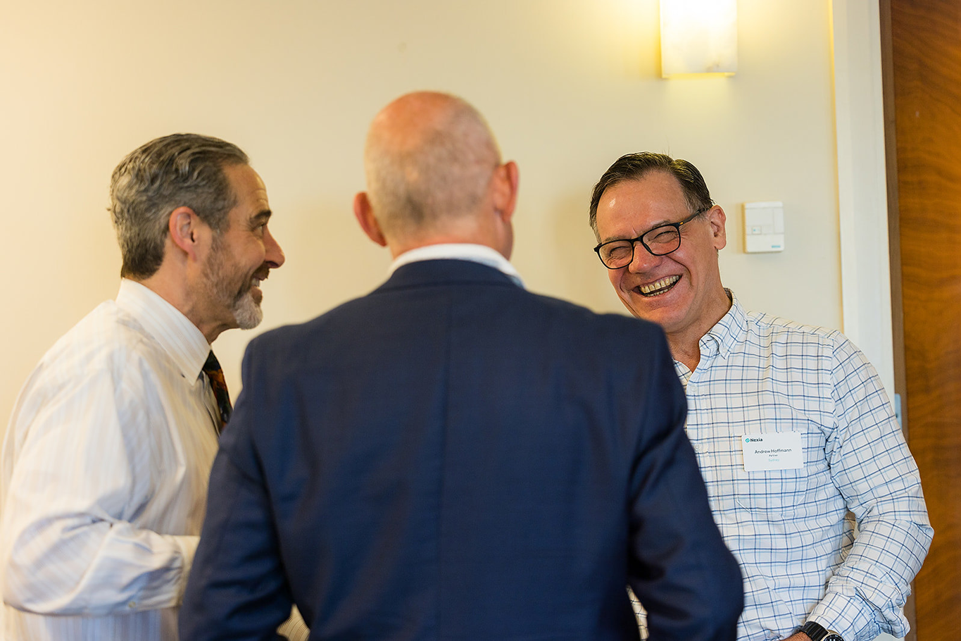 Three male Nexia employees from the USA and Australia having a light discussion